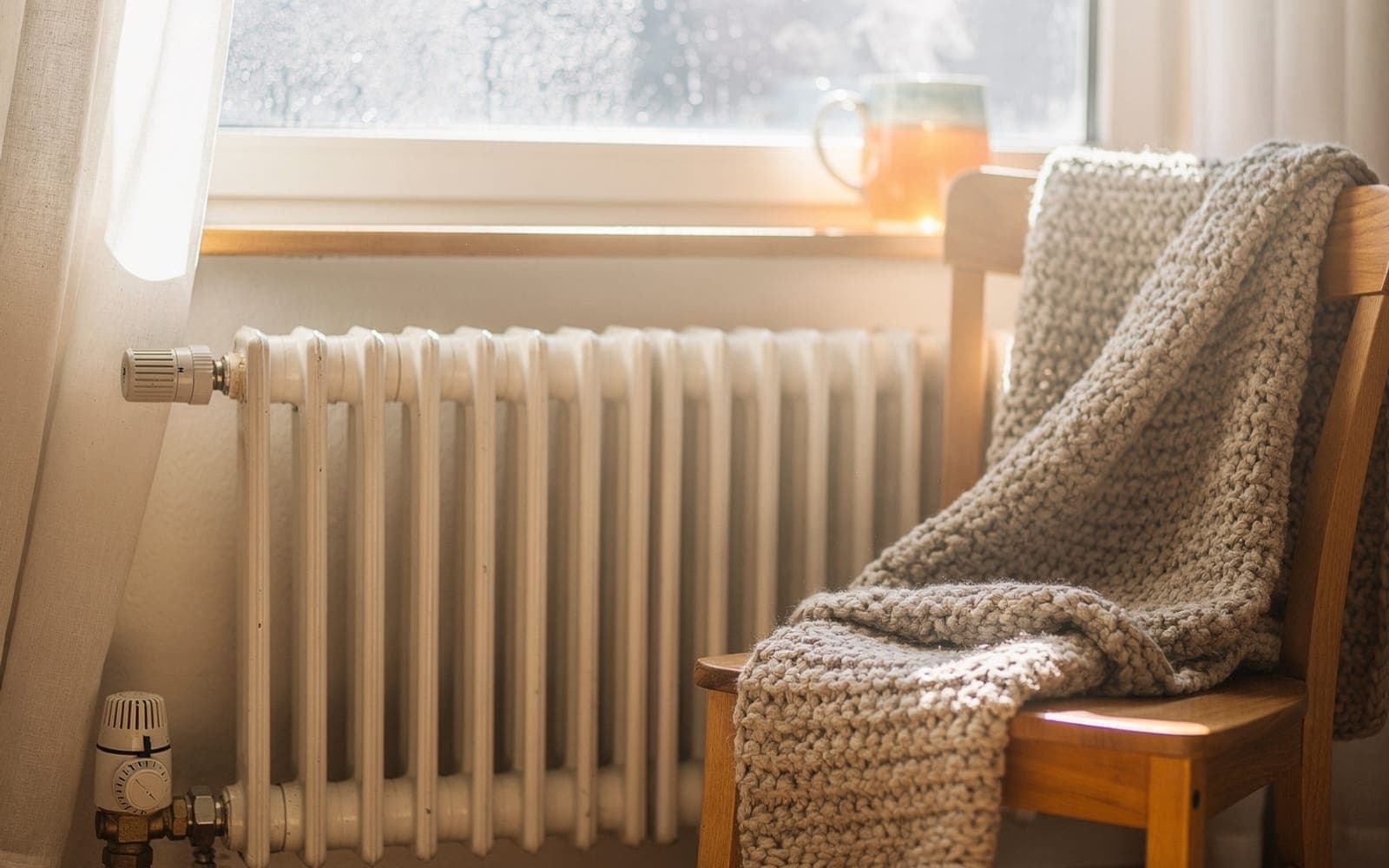 Heizkörper mit Thermostat unter einem sonnigen Fenster