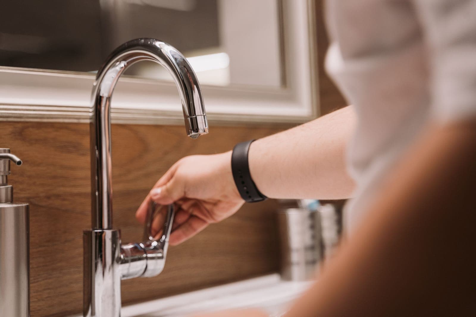 Hand am Wasserhahn eines Waschbeckens